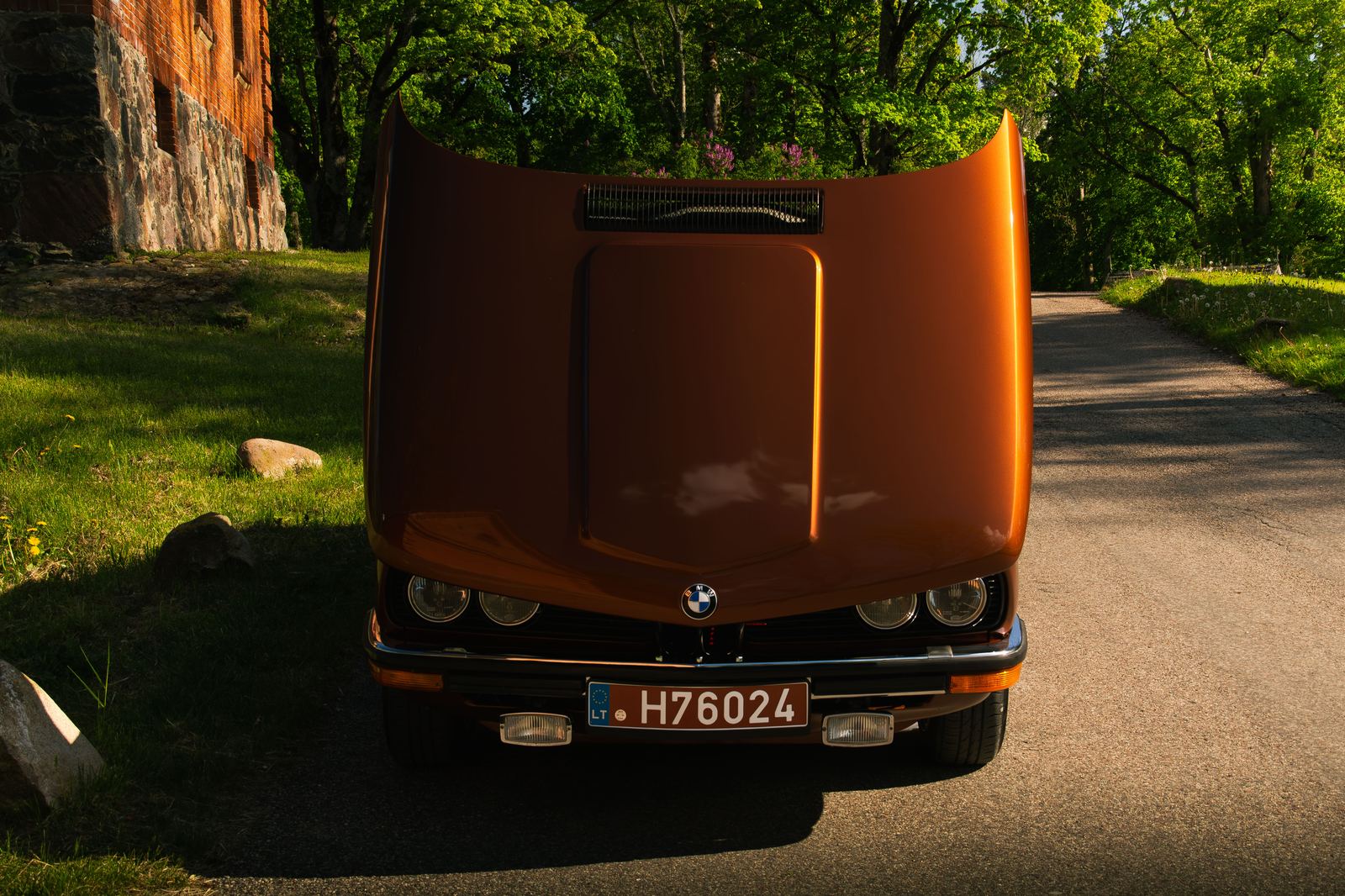 Orange BMW E28 front-on, forest road